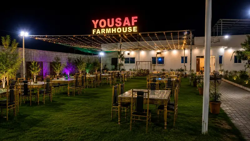 Evening dinner setup with gold chairs and fairy lights on the lawn at Yousaf Farmhouse